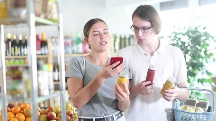 Couple young man and woman buyers scanning qr code for fresh smoothies in bottle in grocery store