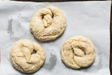 Overhead view of homemade pretzels dough on a baking tray, top view of freshly boiled soft pretzel dough on a white background