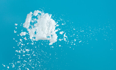 Snow dust element falling over blue sky. Fluffy White snow splash flying or throwing in mid air. Snowfall on blue background isolated