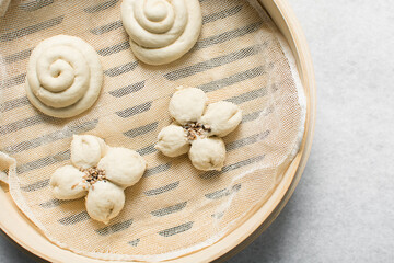 Overhead view of steamed bun in a steamer basket, top view of mantou in a bamboo steamer, process of making steamed milk buns