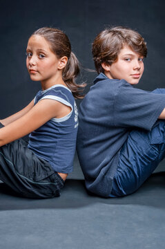 Brother and sister sitting back to back, showing sibling rivalry