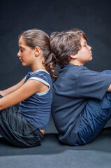 Fototapeta premium Brother and sister sitting back to back ignoring each other