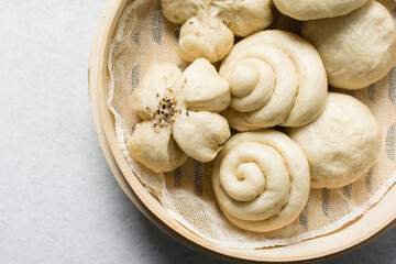 Overhead view of steamed bun in a steamer basket, top view of mantou in a bamboo steamer, process of making steamed milk buns