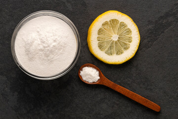 Baking soda in a bowl and spoon with lemon on the table - Citrus Limon
