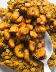 Overhead view of nigerian fried beans and fried plantain on a white plate, top view of nigerian stewed beans and plantain on a white background