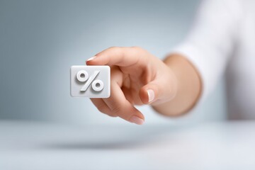 Close up of a hand with fingers tapping on a digital percentage icon representing financial analysis and investment decisions