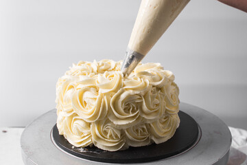 Piping rosettes on a cake using buttercream, Cake being covered in buttercream rosettes, cake being...