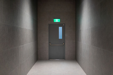 Modern Emergency Exit Door in Minimalist Dark Hallway with Overhead Light and Safety Sign