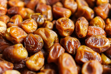 A close-up shot showcasing a heap of glistening dates, their wrinkled surfaces reflecting light, evoking a sense of natural sweetness and healthy indulgence. Perfect for culinary projects.