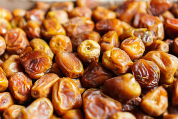 Macro shot of plump, golden-brown dates, glistening with natural sugars. The close-up perspective enhances the rich texture and inviting colors, perfect for a snack or healthy treat advertisement.