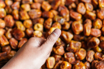 A hand gives a thumbs-up gesture near a pile of succulent dates, signifying approval or satisfaction with the sweet and nutritious snack in a close-up shot for healthy options.