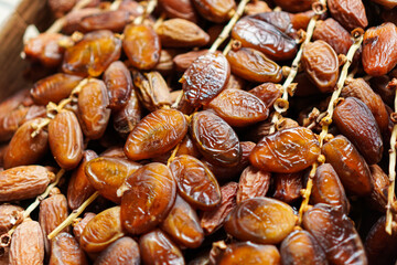 Close-up featuring luscious date fruits still on their stems, showcasing their glistening surfaces and rich brown hues. Ideal for showcasing natural sweetness and healthy snacks, a perfect ingredient.