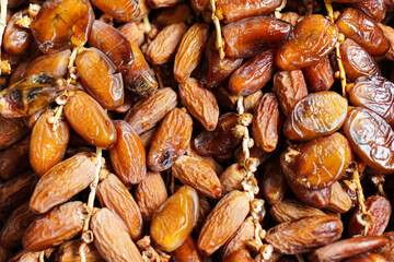 A close-up showcases the rich, glossy texture of dried dates, arranged in a dense pile. The natural light enhances their intricate details, highlighting the sweetness and depth.