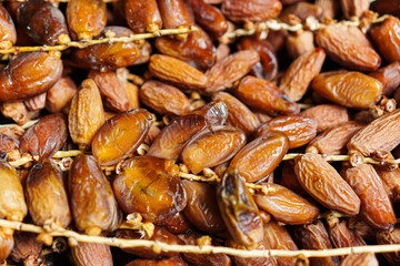 A close-up showcases a cluster of sweet, ripe dates still attached to their stems, their textures glistening in the light, suggesting freshness and natural goodness; a treat to savor.