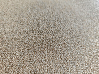 Close-up shot showcasing the intricate texture of a light brown carpet, ideal for interior design or background applications, providing warmth and subtle detail to any visual composition.