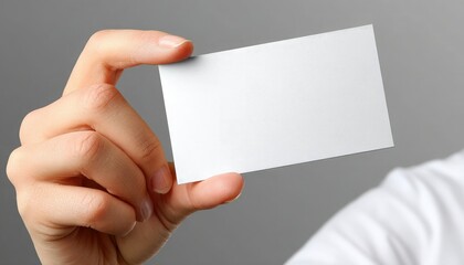 Obraz premium A hand holds a blank white business card against a neutral background.