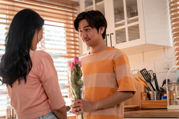 Asian young man surprise and give rose flower to beautiful girlfriend. 