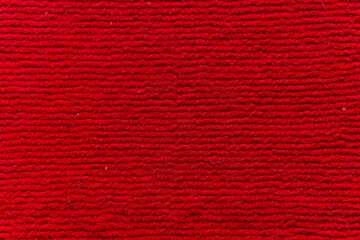 Detailed close-up of a vibrant red fabric with a textured surface, showcasing depth and warmth. Ideal for backgrounds and designs needing a bold splash of color and tactile feel.
