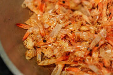 A close-up shot reveals a mass of discarded shrimp shells, their translucent bodies and vibrant orange hues creating an intriguing textural landscape in culinary or food photography contexts.