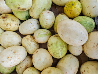 A textured collection of winter melons offers an organic still life. Varied melons share tones of cream, green, and yellow, presenting an image ideal for culinary or health-themed projects.