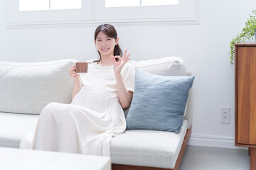 マグカップで飲み物を飲む妊婦