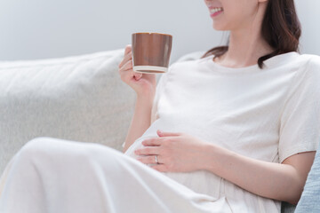 マグカップで飲み物を飲む妊婦