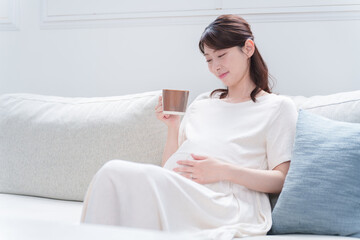 マグカップで飲み物を飲む妊婦