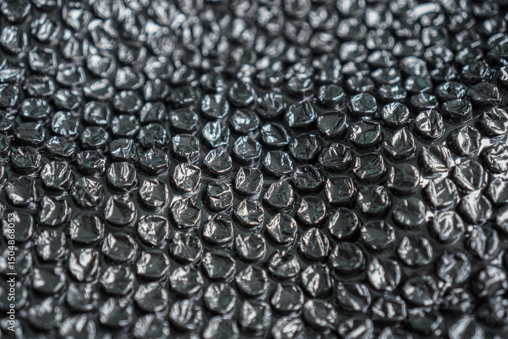 Poster a high-angle close-up showcases a protective layer of dark bubble wrap, ideal for packaging or abstr