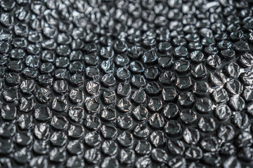 A high-angle close-up showcases a protective layer of dark bubble wrap, ideal for packaging or abstract designs, providing a cushioning texture that offers a versatile background element.