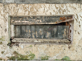 Aged window with a weathered frame revealing textures of decay and neglect. The peeling paint and crumbling walls tell a story of time's passage and abandonment, evoking history and decay.