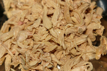 A close-up shot of shredded cooked poultry, perfect for recipe illustrations, meal preparation guides, and healthy eating concepts, showcasing appetizing textures and vibrant detail.