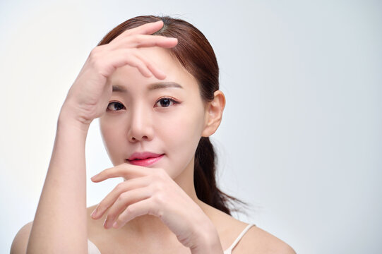 Young Asian Woman with Hands Framing Face in Minimal Studio