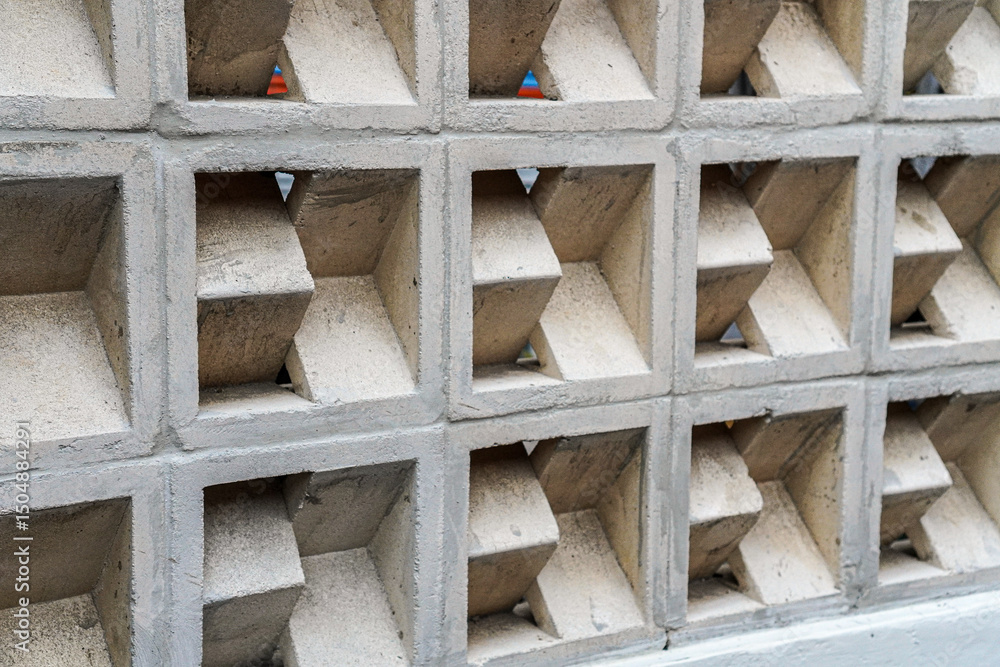 Poster a close-up showcases a geometric concrete wall with repeating square openings. the symmetrical desig