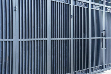 An image featuring a secure metal gate design with vertical bars and decorative scrolls, ideal as a backdrop or texture in urban and industrial design, offering privacy and protection with style.
