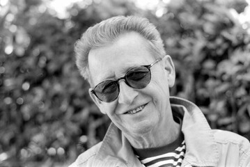 Senior man smiling wearing sunglasses in monochrome analog film style