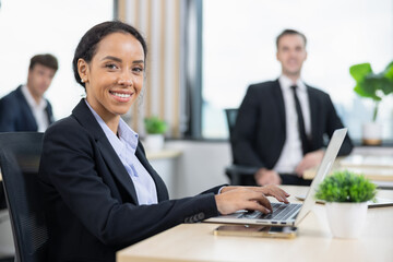 Fototapeta premium African american business woman working with laptop in modern meeting room. Multi-Ethnic Corporate Business Meeting. Female executive handling real estate project. Financial analysis.