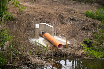 Orange Drainage Pipe by Stream Surrounded by Natural Landscape for Water Management