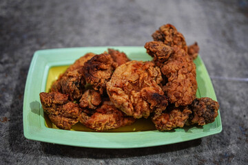 An enticing shot of golden-brown, crispy fried chicken pieces arranged artfully on a vibrant, rectangular dish. The textural contrast and rich color palette make this shot ideal.