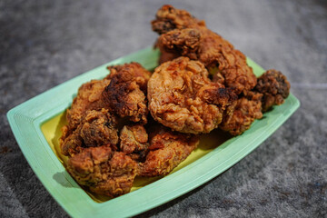 A tempting heap of crispy fried chicken pieces presented on a vibrant plate, perfect for meal-related themes. This delicious poultry is ideal for culinary advertising or stock.