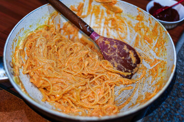 A tantalizing display of creamy spaghetti, elegantly tossed in a vintage pan, presented with a worn...