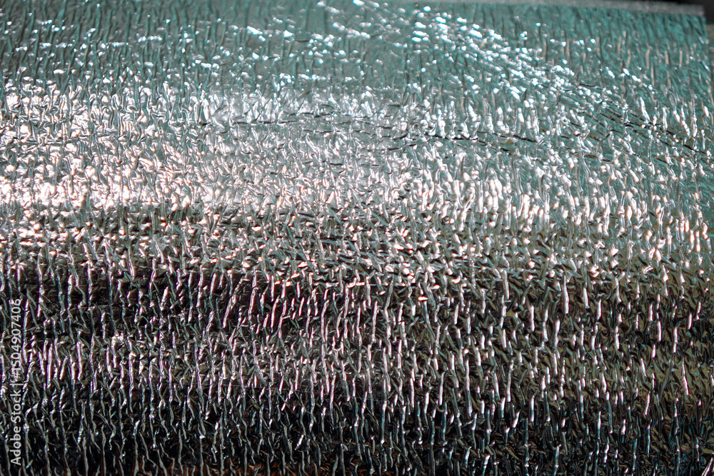 Poster close-up of a shiny, metallic texture with varied lighting creates a reflective backdrop. the irregu
