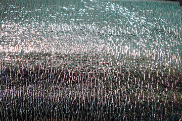 Close-up of a shiny, metallic texture with varied lighting creates a reflective backdrop. The...