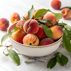 Freshly picked peaches in a bowl with green leaves on a bright white wooden table