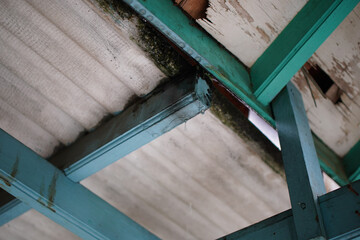 A low angle shot captures the essence of a distressed interior roof, showcasing aged paint, water...