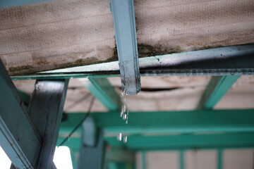A close-up captures water droplets cascading from a metal structure, blurred background elements...