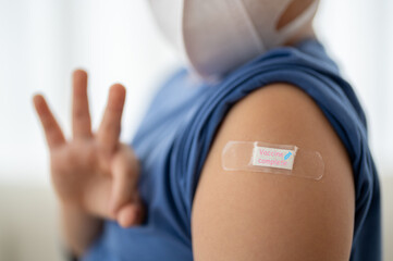 Asian boy making an OK hand gesture after vaccination with bandage on arm, child health care,...