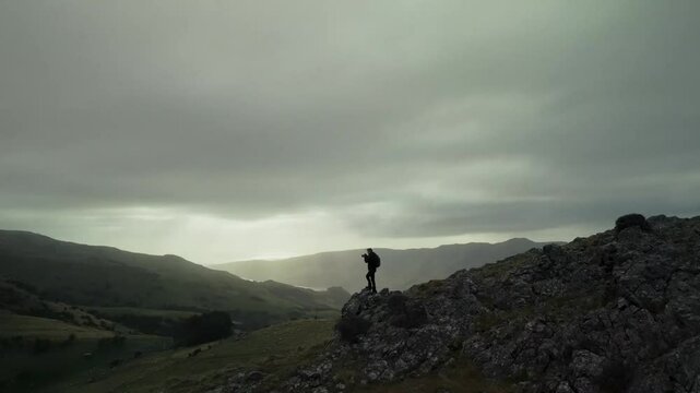 drone footage of a man taking a photo on a mountain ridge