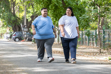 Obesity Concept- Indian couple walking together at summer park to loose weight. Plus size friends...