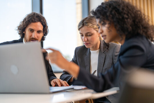 Startup team brainstorming, planning and collaboration with laptop, innovative teamwork and creative strategy in tech environment, featuring multicultural professionals in modern business meeting