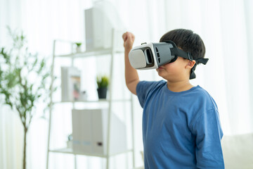 Asian boy playing with vr headset at home interacts with virtual world through immersive technology, future of learning, metaverse education, digital play, entertainment home tech innovation gaming